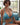 Woman in a blue bikini sitting on a couch with a blurred background