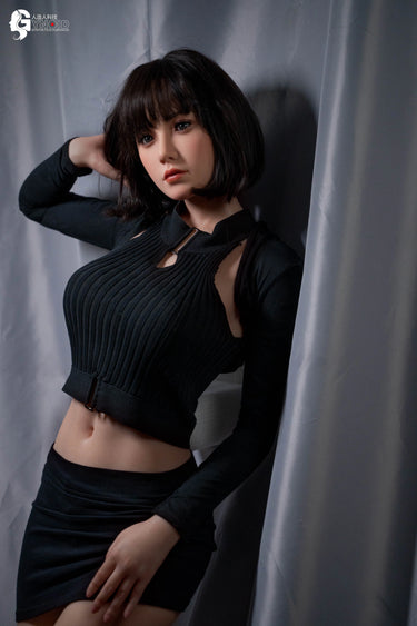 Woman in a black outfit posing against a gray curtain