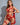 A woman wearing a red lingerie set with lace details and a G-string design, showing her curves.