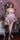 Woman in a pink dress standing in a room with decorative furniture.