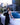 Woman in a black dress leaning against a white car with a cityscape background