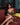 Woman in a gold dress sitting on a red couch with a blurred background