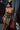 Woman in a gold and black patterned dress standing indoors with a blurred background