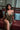 Woman in a gold dress sitting on a red couch with a blurred background