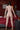 Naked person standing in a bedroom with red bedding and a map on the wall.