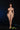 Naked woman standing against a black background with a green object on the ground.
