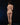 Naked person standing on a black background with green leaves on the ground.