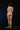 Naked person standing on a black background with green leaves on the ground.