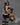 A highly realistic sex doll sitting on a black bench wearing gym wear.