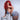 Side view of a highly realistic sex doll with red hair flaunting herself on a chair in blue lingerie.
