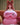 Person wearing a large pink inflatable costume with cat ears on a couch.