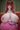Person with fox ears sitting on a pink cushion against a green curtain background