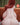 Person with red hair sitting on a couch in a room with a lamp and curtains.