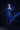 Person in a blue dress with long hair and black gloves against a dark background