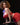 Woman in a red outfit posing on a chair against a black background