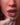 Close-up of a person's mouth with a gloved hand, wearing gold hoop earrings, and the brand 'Ridmii' visible.