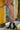 Person wearing black high-heeled boots in a room with yellow walls and a window.