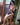 A sex doll with blue hair sitting on a chair near a window in a violet lingerie.