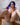A highly realistic sex doll with violet hair wearing a black panty laying on a white colour bed.