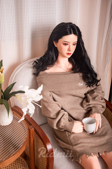 Person wearing a brown sweater holding a cup in a cozy indoor setting