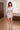 Woman in a white nightgown standing in a bedroom.