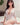 Woman in a white outfit sitting on a bed with a neutral background