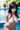 Woman in a white bikini by a pool with plants in the background