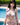 Woman in a bikini standing by a pool with greenery in the background