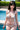 Woman in a bikini standing by a pool with greenery in the background
