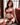 Woman in red lingerie sitting on a red couch in a well-lit room.