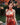 Woman in a red floral dress standing in a garden with cherry blossoms