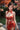 Woman in a red floral dress standing in a garden with cherry blossoms