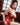 Woman in a red floral dress sitting indoors with wooden paneling.