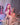 Sex doll with pink hair sitting on a chair in a room with a poster and decor.