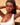 Woman with braided hair wearing a white top against a beige background