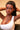Woman with braided hair wearing a white top against a beige background
