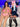 Two realistic sex dolls sitting next to each other, one wearing a pink-trimmed pink bikini and the other a schoolgirl outfit with blue and white stripes. Both dolls have long black hair and are made with a silicone head and body.