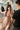 Sex doll being adjusted by a person in a room with a mirror.