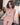 Person wearing a white lace lingerie set in a room with a checkered floor and pillows.