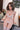 Person wearing a white lace lingerie set in a room with a checkered floor and pillows.