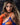 A real silicone sex doll named Daisy with long brown hair and beige skin, wearing a blue and orange outfit.