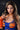 A real silicone sex doll named Daisy with long brown hair and beige skin, wearing a blue and orange outfit with a crop top and orange boobs.