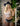 The image shows a highly realistic sex doll with long golden hair, wearing a pink lacey white top and a blue hat. The doll has a lifelike appearance with detailed facial features and is posed in a manner that highlights her natural curves.