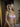 Woman wearing a pink bra and underwear set in a softly lit room.