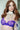 Person wearing a purple lace bra and silver choker with 'Nudist' branding.