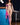 Naked person standing in a room with blue tiled walls and a bar stool.