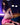 Person wearing a pink outfit with fishnet stockings in a dimly lit room.