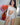 Woman in a white off-shoulder top and shorts standing indoors with flowers and a painting in the background.