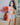 Sex doll standing in a room with flowers and a painting on the wall.