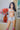 Sex doll standing in a room with flowers and a painting on the wall.